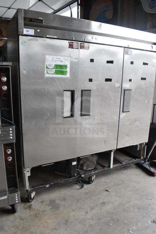 True T-72 Commercial 3 Door Reach-In Cooler, stainless steel, 115 volts, 1 phase, on casters, visible wear.