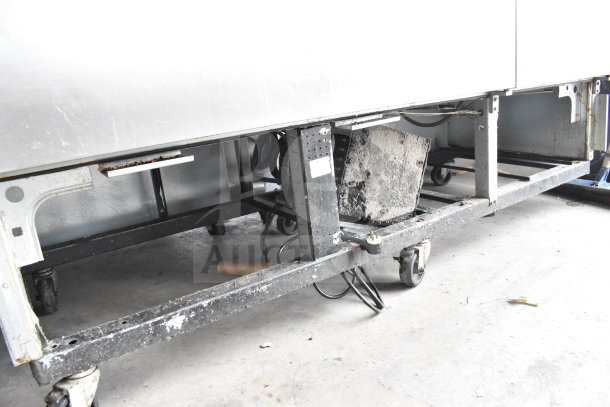 True T-72 Commercial 3 Door Cooler, visible undercarriage, shows wear, 115V, 1 Phase, casters for mobility.