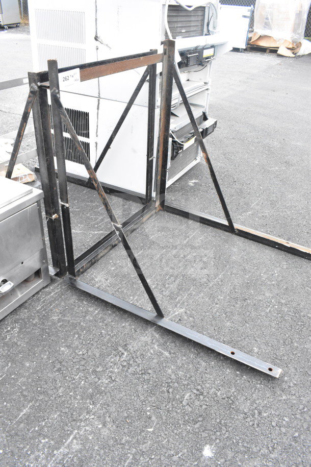 Two metal frames with support bars, in used condition, set against industrial equipment. Label reads "262 AV".