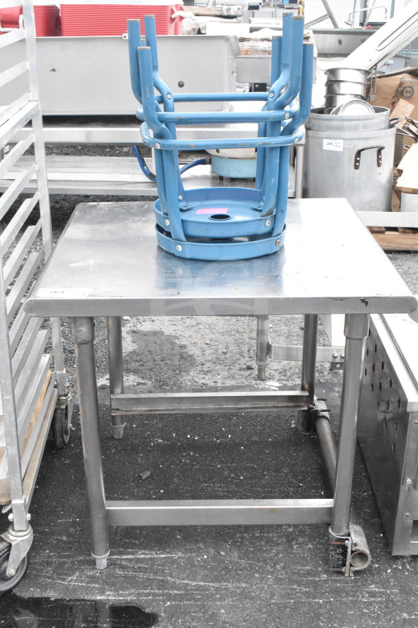 Silver commercial table with two stacked blue stools, sturdy metal construction, used condition, ideal for industrial use.
