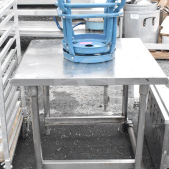 Silver commercial table with two stacked blue stools, sturdy metal construction, used condition, ideal for industrial use.