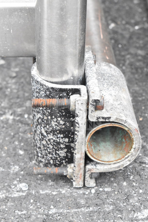 Close-up of worn metal table leg joint with rusty screws, indicative of a commercial table's base condition.