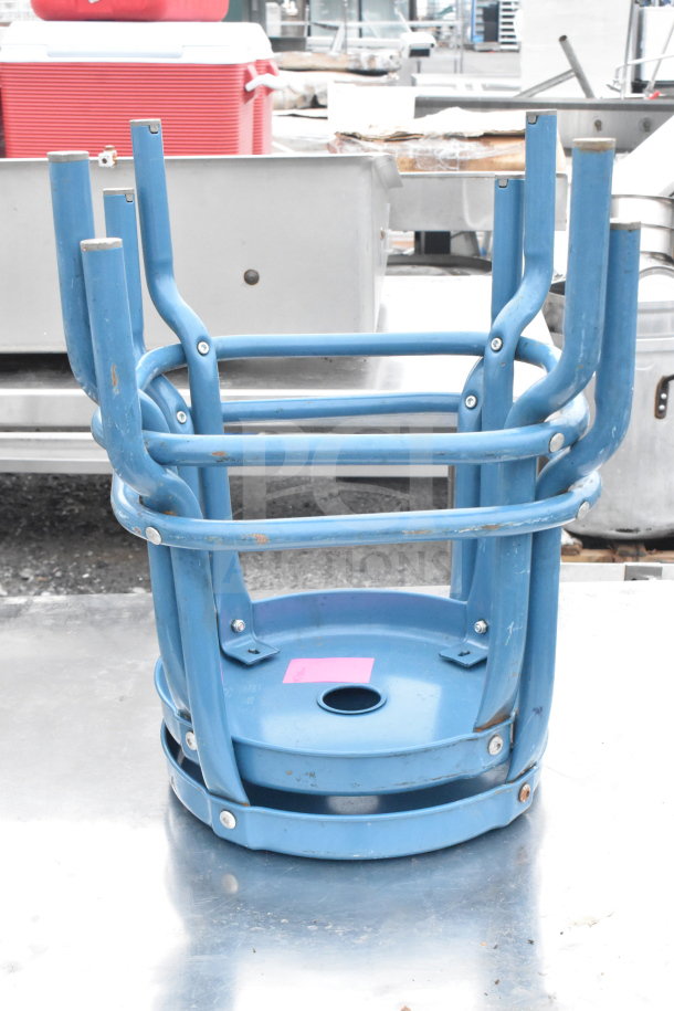 Blue metal stools stacked, showing signs of wear. Part of an auction lot with a commercial table and additional stool.