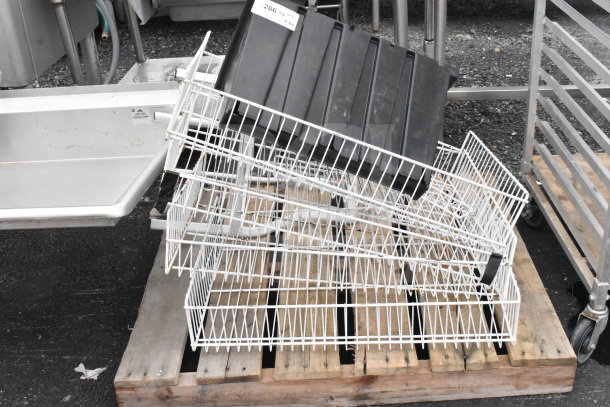 Six various storage baskets, including black and white containers, on a wooden pallet. Good condition.
