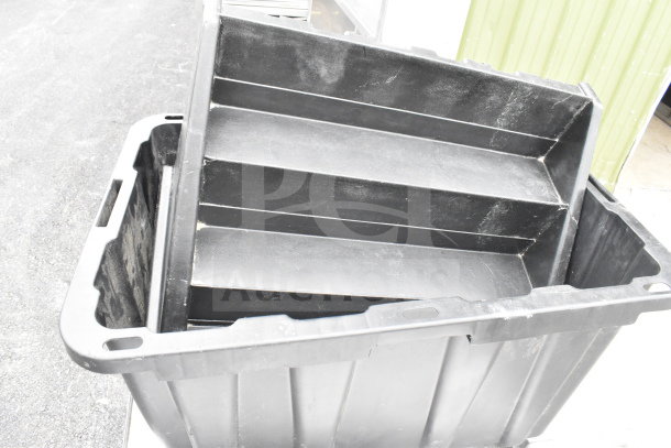 A black plastic container with multiple tiers, partially filled with black trays. The container appears used.