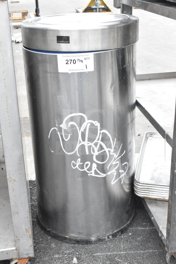 Simplyhuman stainless steel trash can, cylindrical shape, minor graffiti, auction tag indicating quantity and auction site.