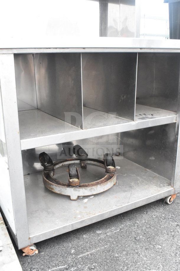 Commercial counter with two over shelves, two under shelves, on commercial casters. Made of metal, shows signs of wear.