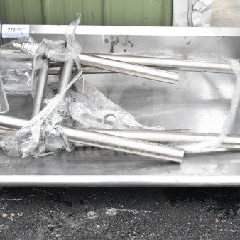 Commercial table with metal legs, unassembled, on a flatbed. Includes packaging. Condition appears used.