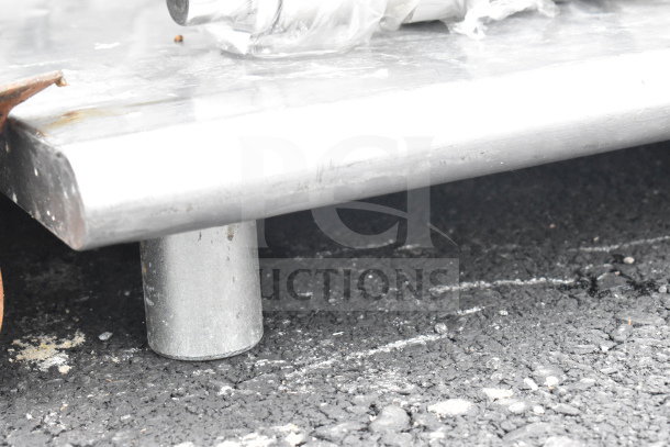 Commercial table with metal legs, sturdy construction, shows signs of wear on the surface. Ideal for industrial use.