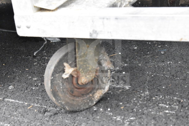 Commercial pan transport rack with durable commercial casters. Visible wear indicates prior use. Ideal for kitchen logistics.