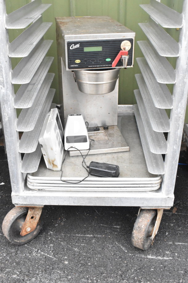Commercial pan transport rack with Curtis coffee machine on casters, used condition, visible wear and rust on wheels.