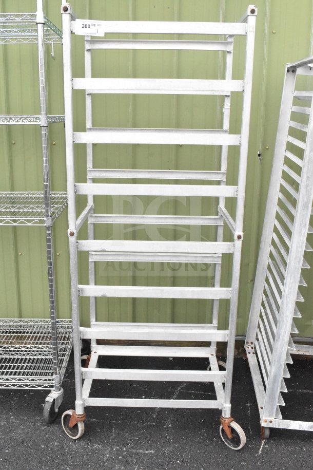 Commercial pan transport rack with multiple shelves on sturdy casters, industrial-grade, silver finish, some visible rust.