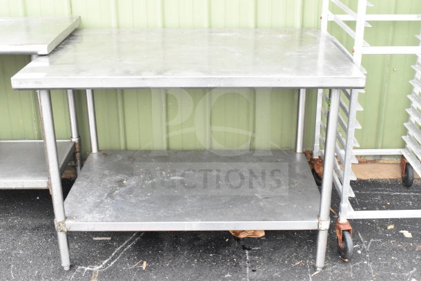 Commercial stainless steel table with under shelf. Visible wear on surfaces. Ideal for kitchen or industrial use.