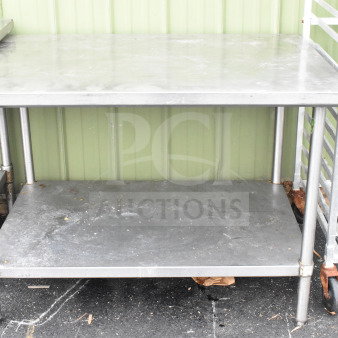Commercial stainless steel table with under shelf. Visible wear on surfaces. Ideal for kitchen or industrial use.