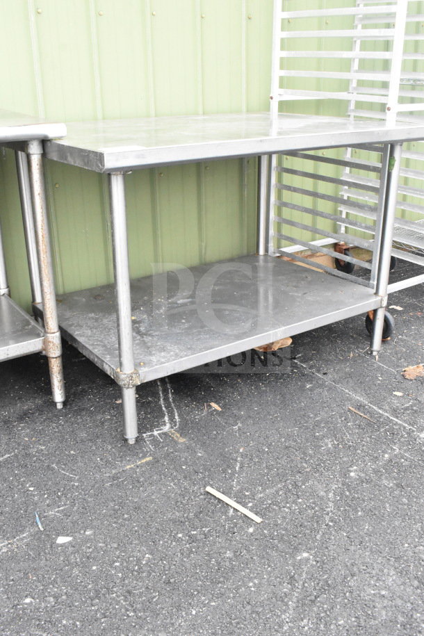 Commercial metal table with under shelf, sturdy construction, minor surface wear, ideal for kitchen or workspace use.