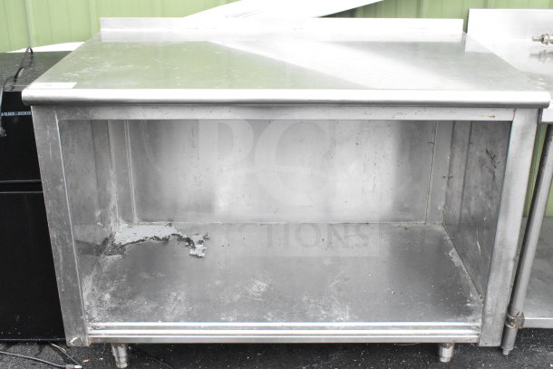 Commercial stainless steel table with under shelf, signs of wear, suitable for kitchen or industrial use.