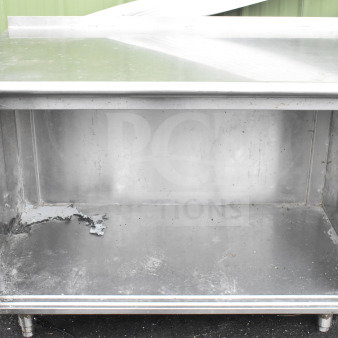Commercial stainless steel table with under shelf, signs of wear, suitable for kitchen or industrial use.