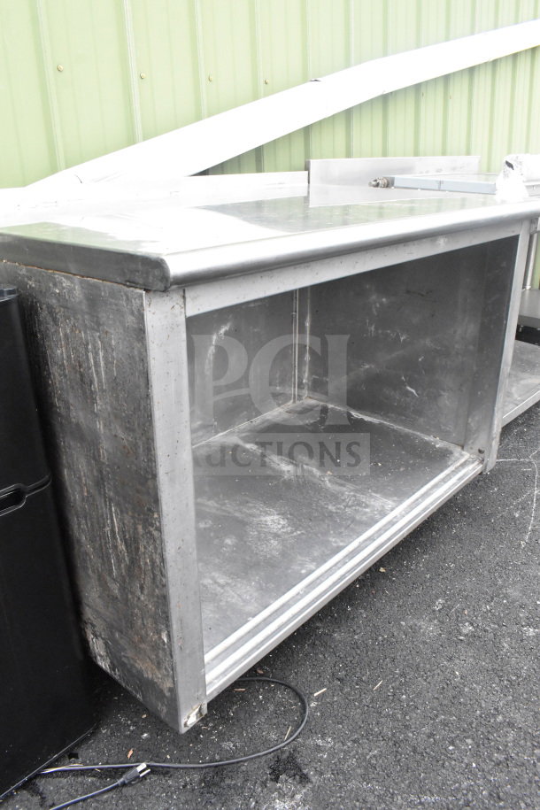 Stainless steel commercial table with under shelf, visible wear and weathering on surface, suitable for heavy-duty use.