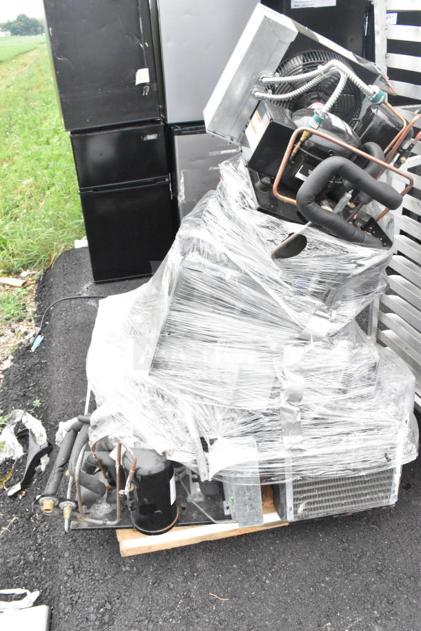 Seven various compressors, including a Copeland, wrapped for auction. Good condition, bundled on a wooden pallet.