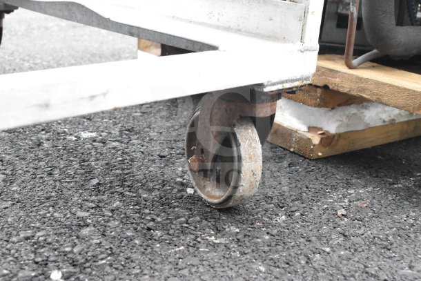 Commercial pan transport rack with sturdy metal frame, mounted on durable, slightly rusted commercial casters.