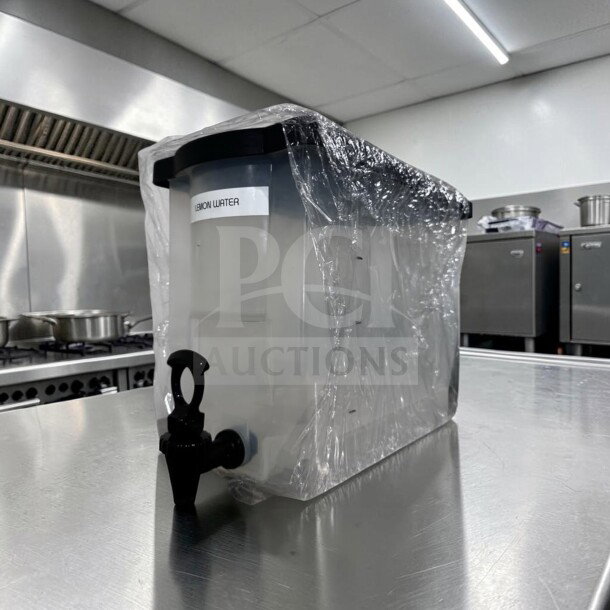 Like-new plastic cold juice dispenser with spigot, clear body, and label reading "Lemon Water," model MIS-S-DISP-1227.
