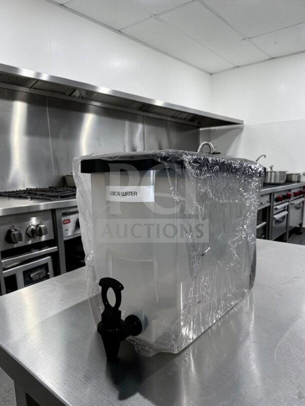 Unbranded cold juice dispenser in like-new condition, plastic with spigot, labeled "lemon water," wrapped for protection.