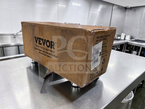 Brand new VEVOR GM-001 3000W electric grain mill grinder in sealed box on metal table, 110–120V model.