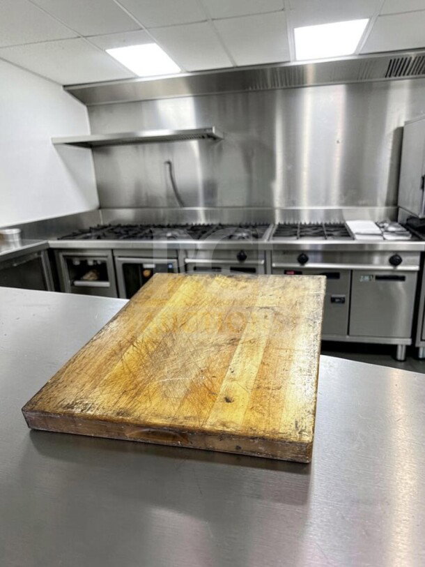 Large maple butcher block cutting board, 24"x18", shows signs of use, non-slip feet, suitable for restaurant use.