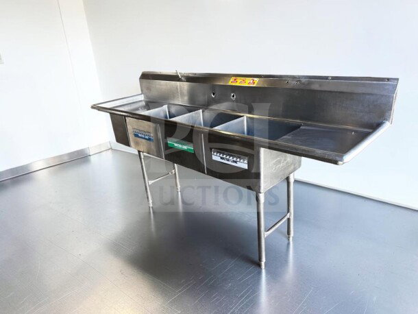 Commercial three-compartment stainless steel sink with dual drainboards, high backsplash, and adjustable legs in flawless condition.