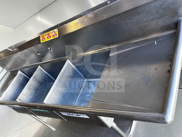 Commercial three-compartment stainless steel sink with dual drainboards, high backsplash, and adjustable legs in flawless condition.