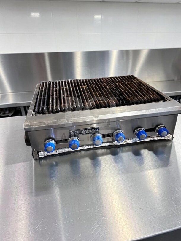 American Range 48" radiant gas charbroiler with six burners, heavy-duty cast-iron grates, stainless steel, fully operational.