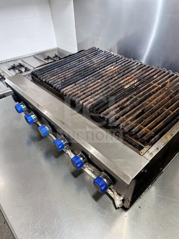American Range 48" radiant gas charbroiler with six burners, heavy-duty cast-iron grates, and blue control knobs. Stainless steel.