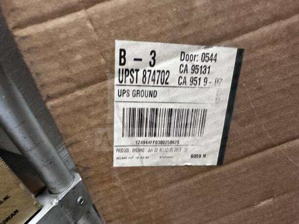 Cardboard box with a shipping label visible. Label includes barcodes, item numbers, and addresses for UPS Ground.