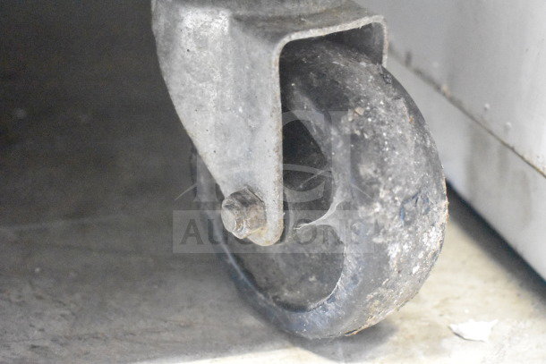 Alt text: Close-up of a commercial caster wheel from a True T-23F reach-in freezer, showing wear and metal bracket.