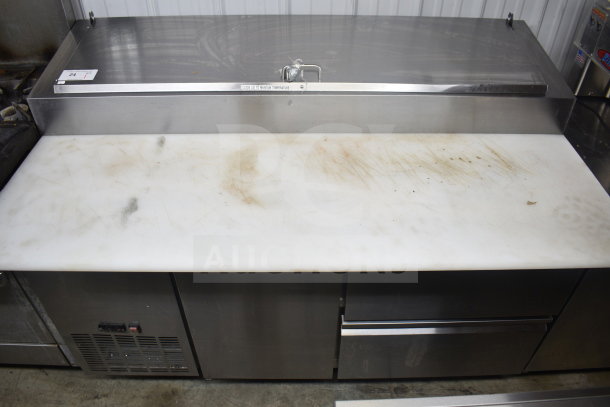 Avantco commercial pizza prep table with two drawers, one door, and commercial casters. Features stainless steel body and cutting board.