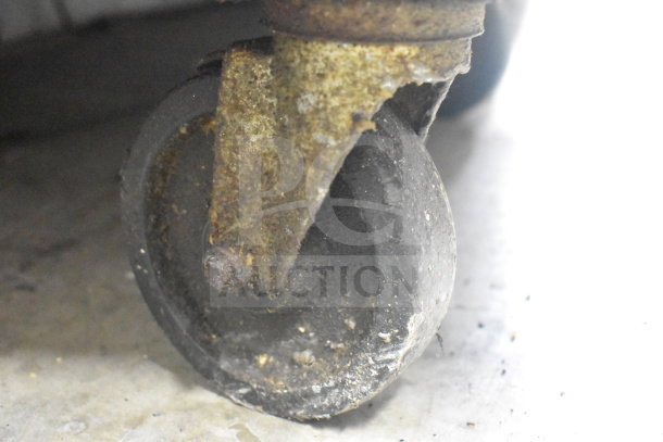 Close-up of a worn commercial caster wheel from a Southbend gas-powered range. Visible rust and dirt indicate moderate wear.