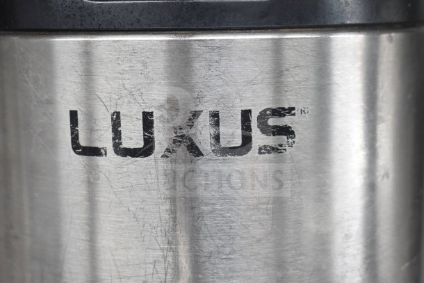 Fetco Luxus L3D-10 hot beverage holder with noticeable wear. Brand name "LUXUS" marked on stainless steel surface.
