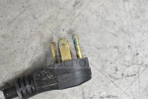 Close-up image of a used T&P PSL-80-RA2 induction wok range power plug, showing worn, slightly corroded prongs.