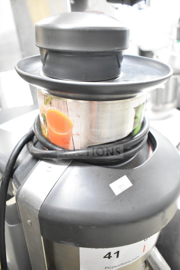 Robot Coupe J100 Commercial Juicer, 115V, 1 Phase. Black and stainless steel finish with visible power cord and auction tags.
