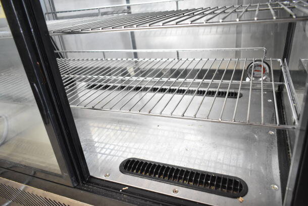 Omcan 27157 refrigerated display case with glass doors and wire shelves. Features 110 Volts, 1 Phase. Visible temperature gauge.