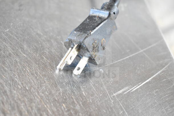 A close-up of a black electrical plug for the Cadco XAFT133 convection oven, showing slight wear.