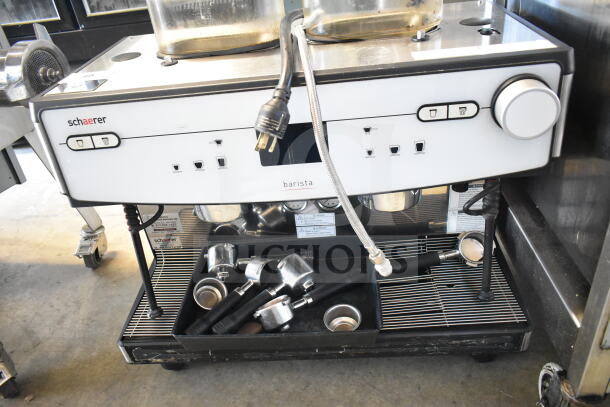 Schaerer Barista commercial 2-group espresso machine with 2 hoppers, 4 portafilters, and 2 steam wands; power cord visible.