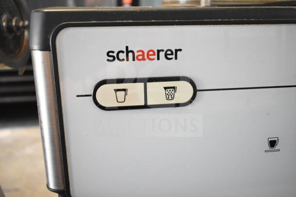 Schaerer Barista commercial espresso machine with 2 hoppers, 4 portafilters, 2 steam wands; logo and controls visible.