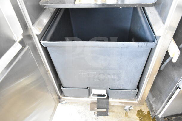 Chicago commercial floor vertical trash compactor with casters, black bin, visible "Trashcube" label, steel construction, used condition.
