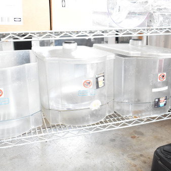 Clear plastic hoppers for drink blending machines on a metal shelf, with visible caution labels and auction tag marked "58."