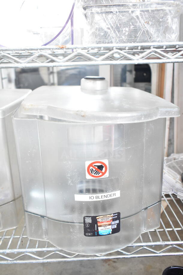 Transparent hopper for a drink blending machine on a wire shelf, marked "10 Blender" with caution symbols, in used condition.