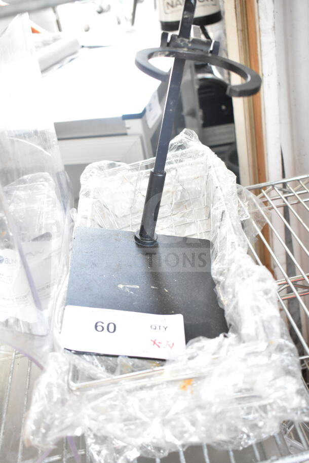 Assorted items including a black metal stand and a clear slushie hopper on a rack, marked with a "60 QTY" tag.