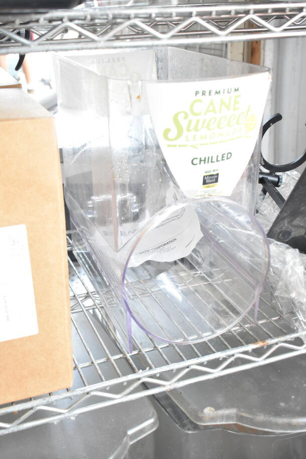 Transparent slushie hopper with "Premium Cane Sweet Lemonade Chilled" label on metal shelf. Includes various items.