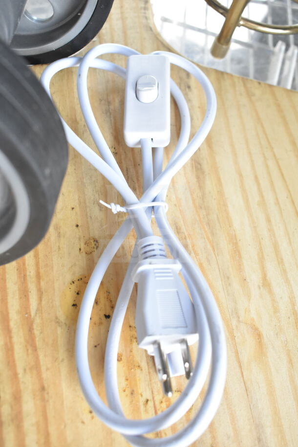 Cord with inline switch resting on wooden surface; part of auction lot with various items including pizza paddle and rolling unit.