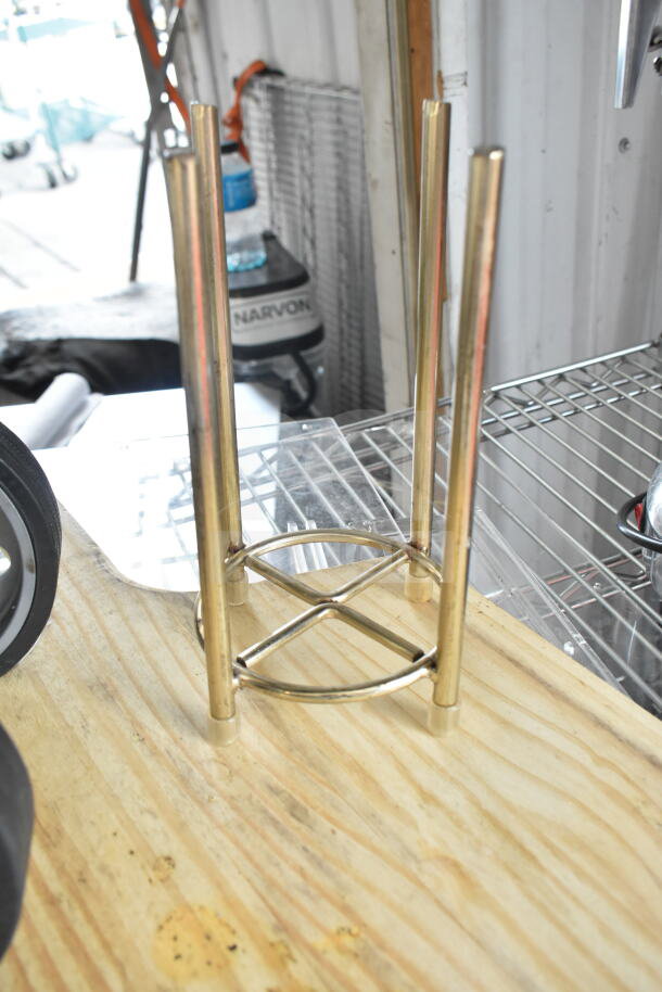 Various auction items, including a metal stand, on a wood surface. Additional items not clearly visible.